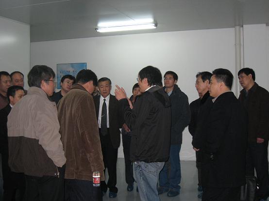 车间里，向电焊机协会参会代表讲解尊龙凯时(中国)人生就是搏半导体整体运行情况